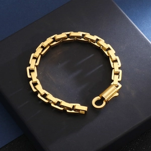 Detail of a thick gold square chain bracelet with a round lobster clasp on a blue block