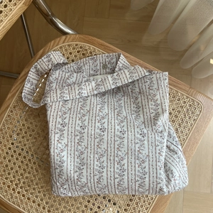 Detail of floral canvas bag featuring magnetic metal clasp and vintage striped pattern