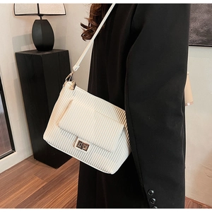 Detailed view of white corduroy shoulder bag with gold rotating lock and textured fabric