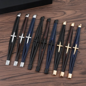 Detailed close-up of woven leather bracelets with alloy crosses on a dark wood background