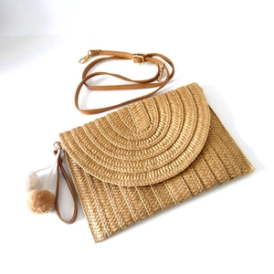 Detail of paper straw woven clutch with beige texture and dual-tone pompom tassel