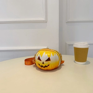 Detail of a small pumpkin-shaped crossbody bag on a white table with a coffee cup