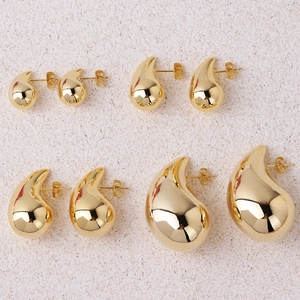 Detailed comparison of four sizes of polished golden teardrop earrings on a stone surface