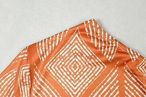 Detailed close-up of orange geometric print fabric and stitching on a commute dress