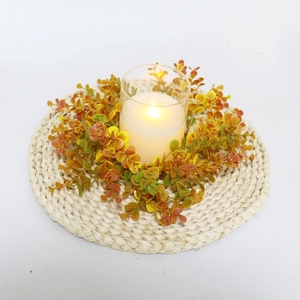 Detail of violet eucalyptus leaf wreath with LED candle and round woven placemat
