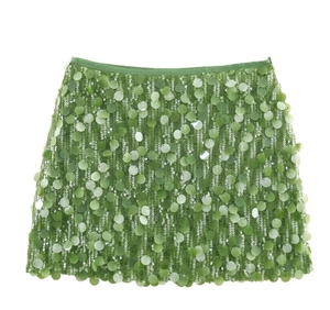 Close-up of sparkling light green sequins on a stylish mini skirt with metallic reflection