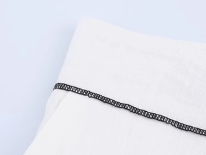Vue macro détaillée du passepoil noir et des coutures sur tissu blanc en coton et lin