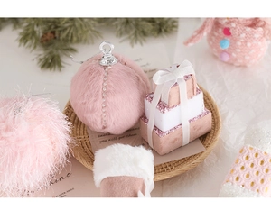 Pink faux fur Christmas ornaments and festive gift box decorations in a woven tray
