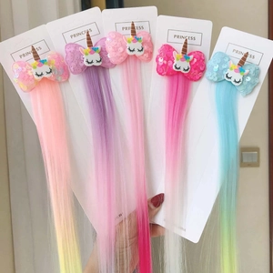 Detail of colorful unicorn hair clips with sequin bows and long synthetic hair extensions