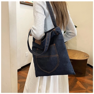 Dettaglio della borsa tote in denim blu scuro con tasca classica e patch in pelle