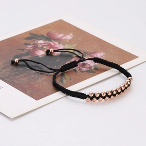 Detail of black woven cord bracelet with double-row rose gold beads on floral card