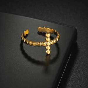 Adjustable gold plated stainless steel bead ring featuring a cross charm on black surface