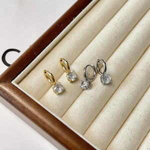 Detail of gold and silver hoop earrings with round cubic zirconia in a jewelry box