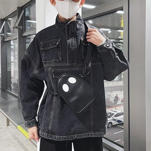 Street style black crossbody bag with white eye detail worn by model in casual setting