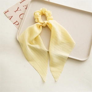 Close-up of light yellow chiffon scrunchie with long ribbons and pleated texture