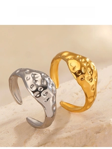 Close-up of gold and silver hammered stainless steel open rings on stone texture
