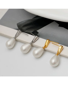 Detail of water drop pearl earrings in gold and silver finish on book pages