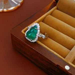 Detail of an open silver ring with a green gourd zircon gemstone in a jewelry box