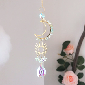 Macro shot of golden crescent moon pendant with green gemstones and clear crystal prism