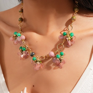 Detailed close-up of a golden layered necklace with colorful stone beads and shell pendants