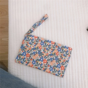 Pochette floreale in cotone con cerniera e cinturino su uno sfondo trapuntato