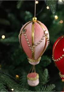 Pink velvet hot air balloon Christmas ornament with pearls hanging on a festive tree