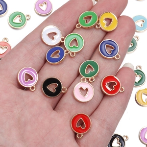 Detailed view of colorful enamel heart pendants in various shades held for size reference