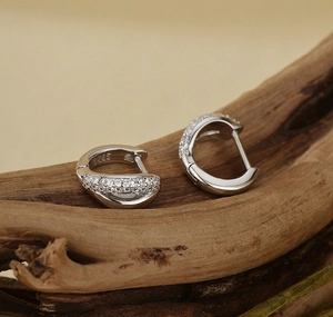 Macro detail of S925 sterling silver hoop earrings with cubic zirconia on wood