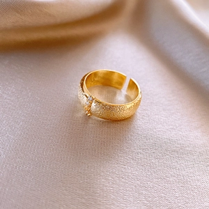 Macro detail of gold matte oval ring with zircon inlay on silk background