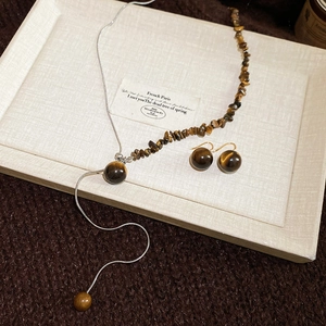 Detail of tiger eye bead necklace and earring set on a premium textured display tray