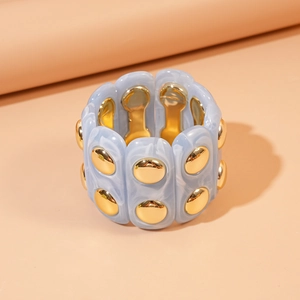 Detail of blue marble acrylic stretch bracelet with gold studs on a neutral prop