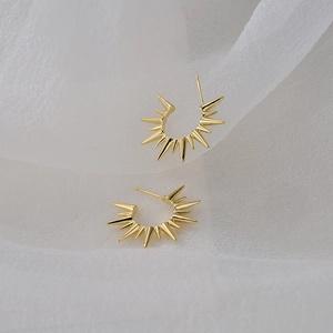 Chic 18K gold plated spiked sunburst earrings on elegant white draped fabric