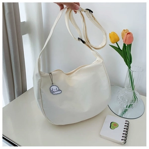 Detail of off-white canvas dumpling bag featuring adjustable strap and cute cloud charm