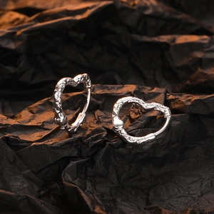 Sliver heart hoop earrings with lava texture design on a dark background