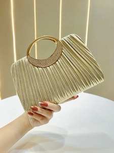 Detail of gold pleated evening bag featuring a rhinestone-encrusted metal round handle