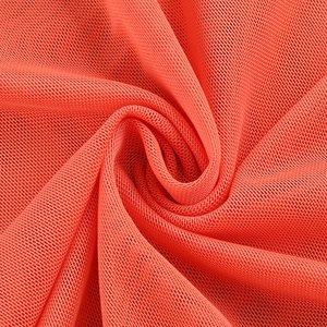 Detailed macro view of orange mesh fabric texture and breathable pleated mesh material