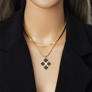 Close-up of double layer gold necklace with black geometric diamond pendant on black blazer