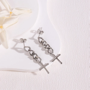 Detailed close-up of silver chain earrings with cross pendants and gothic tassels