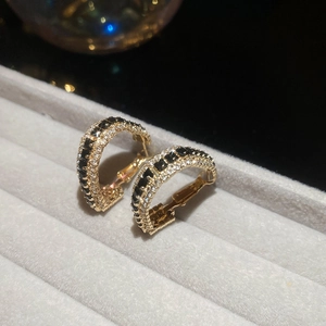 Detailed macro view of U-shaped golden earrings with black stones and white diamonds