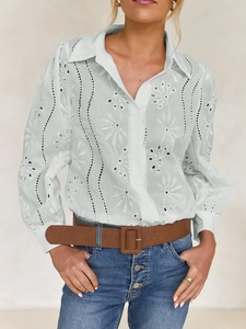 Close-up of intricate floral embroidery and hollow-out detailing on women's white blouse