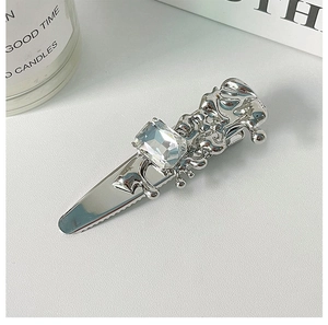Detail of silver liquid metal bow hair clip with a large rectangular clear rhinestone