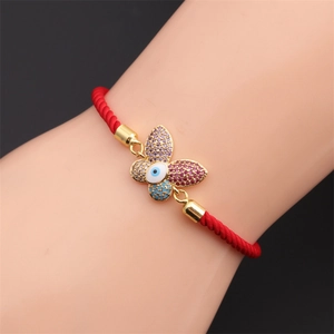 Detailed macro shot of red string butterfly bracelet with colorful zircon evil eye charm
