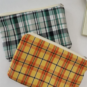 Vue détaillée de pochettes à monnaie en tissu à carreaux vert et orange avec fermeture