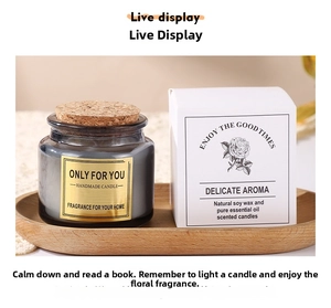 Detail of soy wax candle in black glass jar with cork lid and floral gift box