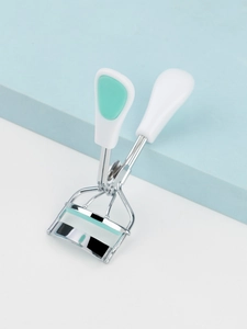 Detailed view of stainless steel eyelash curler with white handle and mint green grip