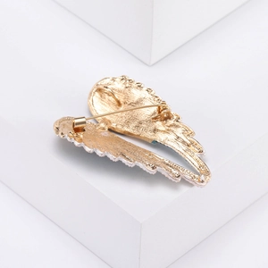 Detail view of the gold-plated metal back and safety pin clasp of the angel wing brooch