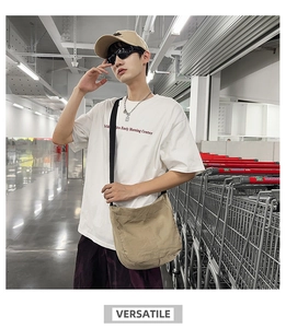 Street style view of khaki canvas crossbody bag paired with a white printed t-shirt