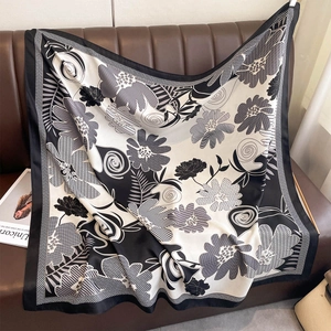 Detail showing high-contrast floral print and silky texture of the square scarf on leather