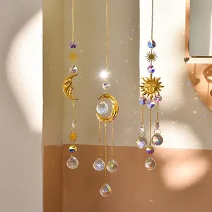 Golden sun and moon crystal suncatchers with rainbow prisms hanging on a sunlit wall