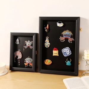 Black wooden shadow box frame for pins and badges with gold latch on a desk